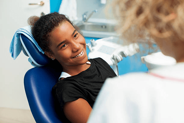 Dental professional offering reassurance to a young patient in a treatment room.