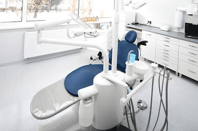 Bright dental operatory with large windows and a blue treatment chair.